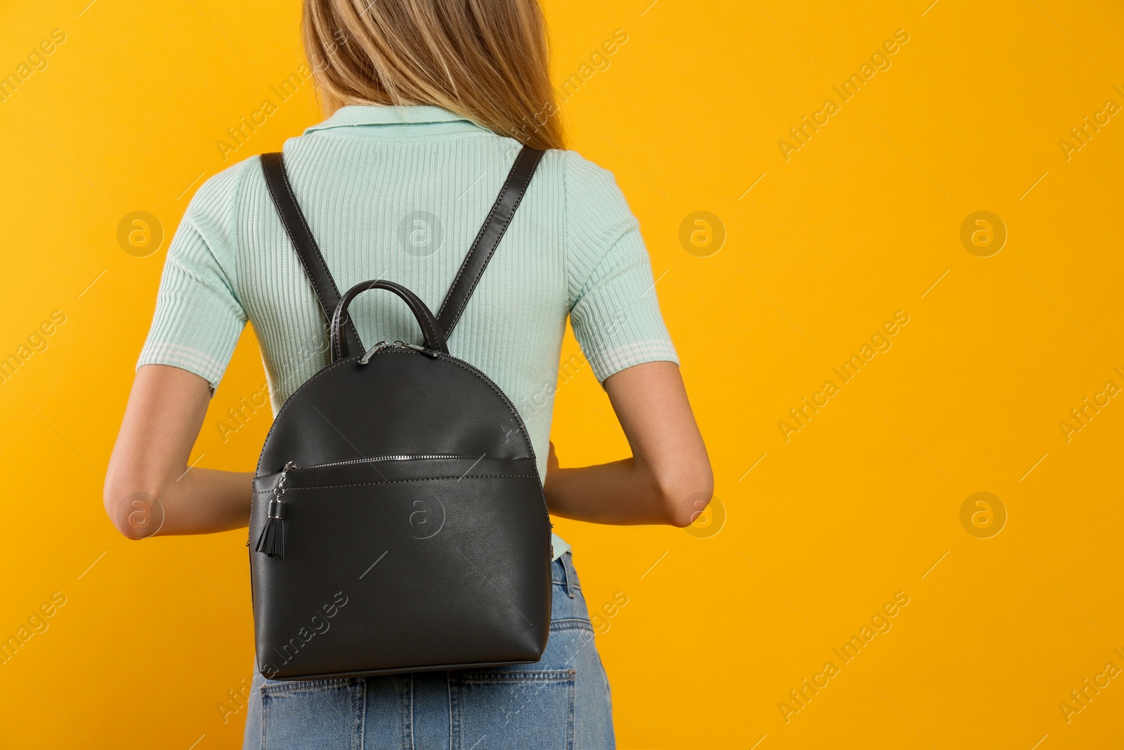 Photo of Closeup view of woman with backpack on yellow background, back view. Space for text