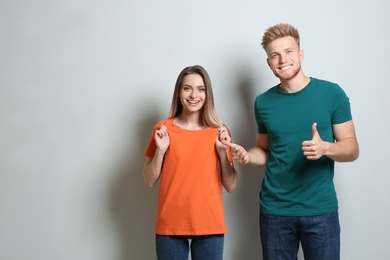 Photo of Young couple wearing blank t-shirts on light background. Mockup for design