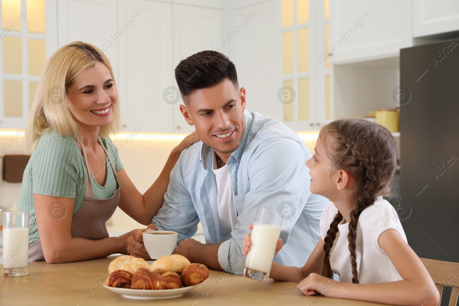 Photo of Happy family eating together at table in modern kitchen