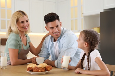 Happy family eating together at table in modern kitchen