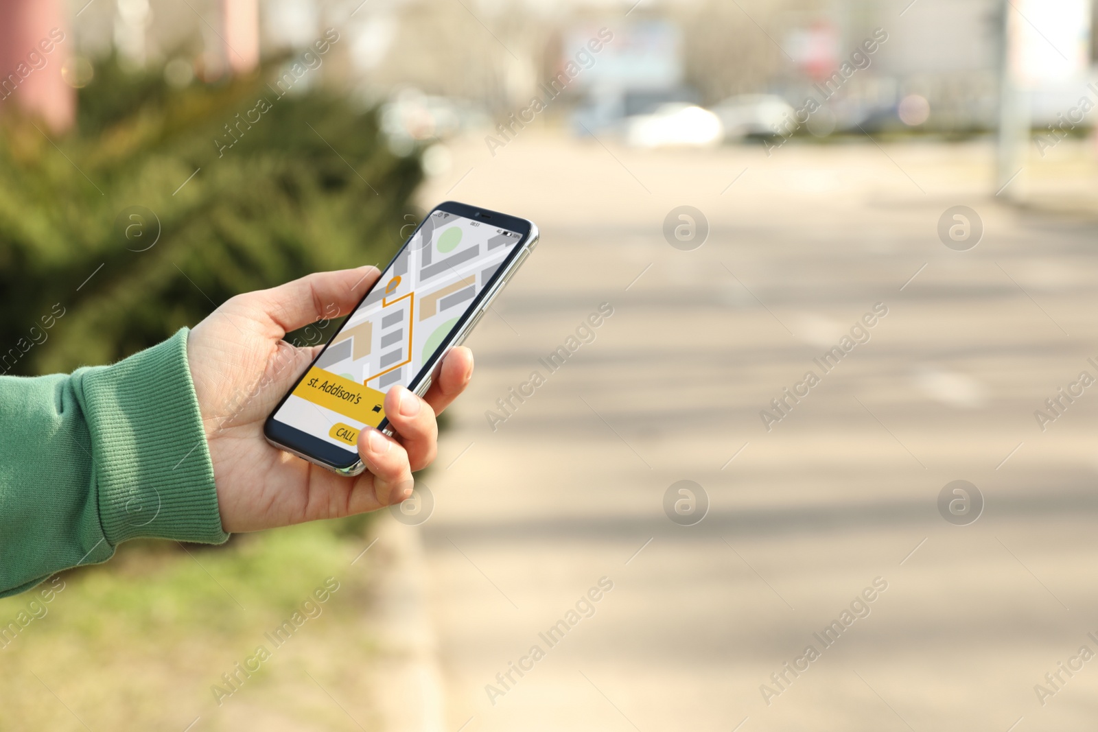 Photo of Man ordering taxi with smartphone on city street, closeup