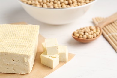 Photo of Cut tofu and soya beans on white wooden table, closeup
