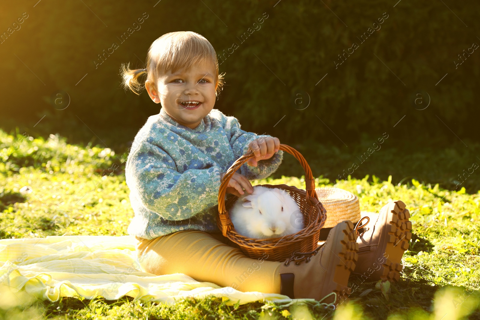 Photo of Happy little girl with cute rabbit on green grass outdoors