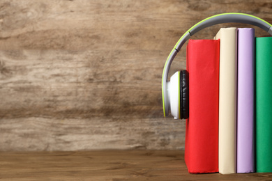 Books and modern headphones on wooden table, closeup. Space for text