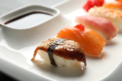 Photo of Plate with delicious nigiri sushi and soy sauce on table, closeup
