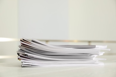 Photo of Stack of documents with paper clips on office table. Space for text