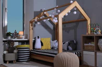 Photo of Stylish child room interior with comfortable house bed and toys