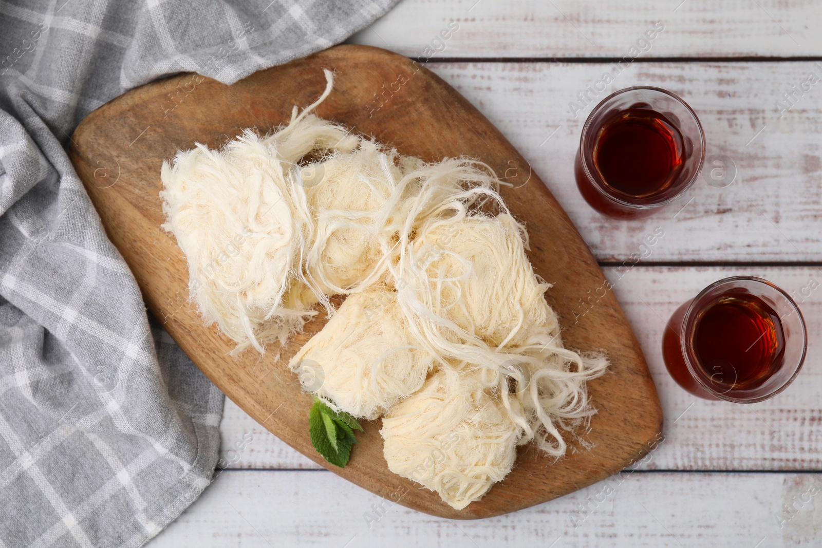 Photo of Eastern sweets. Tasty Iranian pashmak and tea on white wooden table, top view