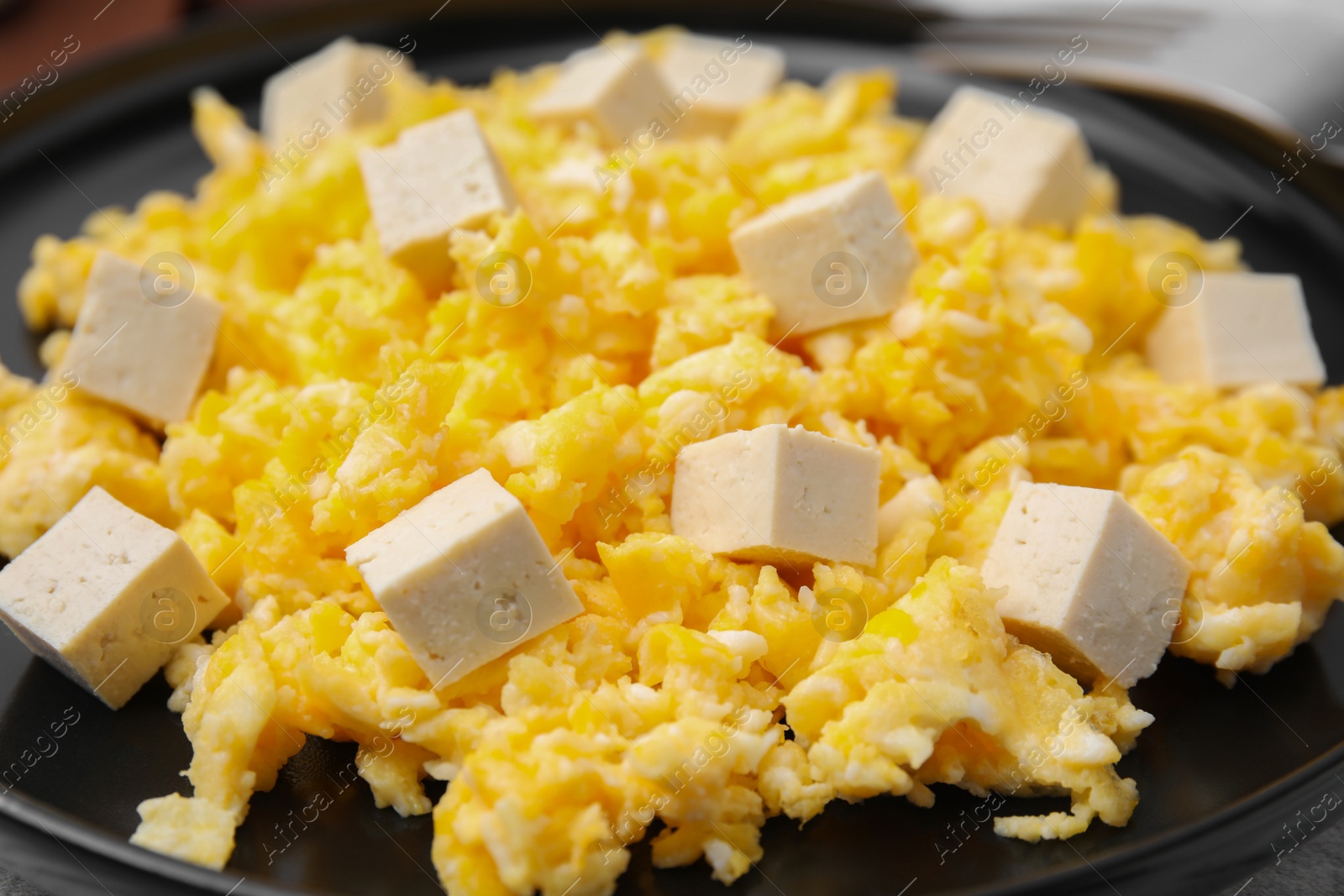 Photo of Plate with delicious scrambled eggs and tofu, closeup