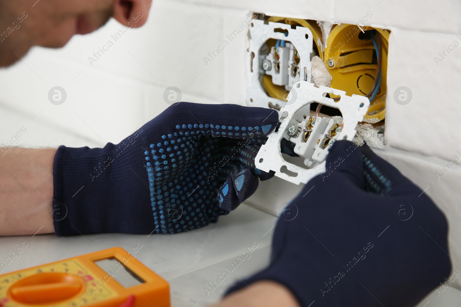 Photo of Professional electrician repairing power socket indoors, closeup