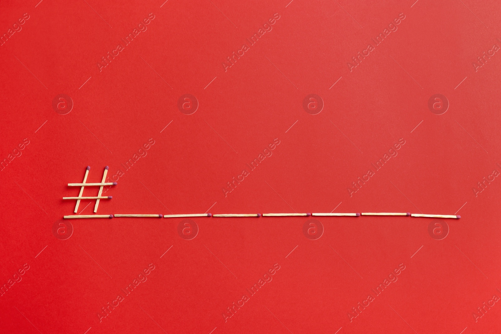 Photo of Hashtag symbol and space for text made of wooden matches on red background, flat lay