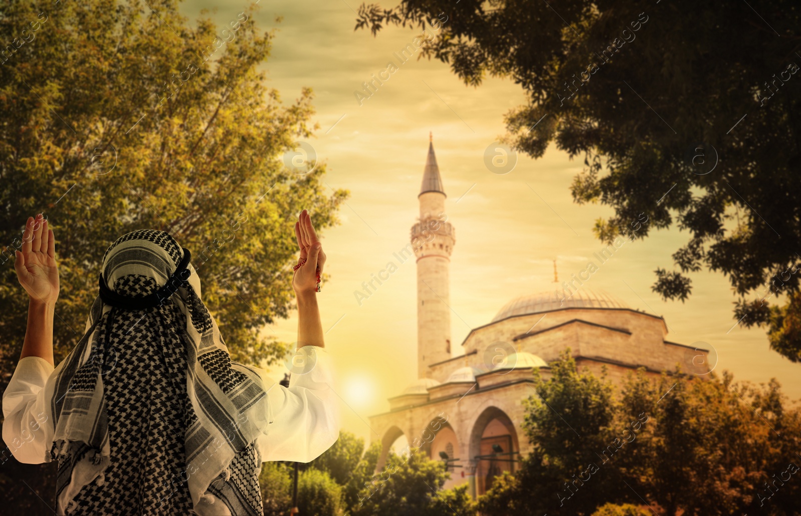 Image of Muslim man praying near mosque at sunset