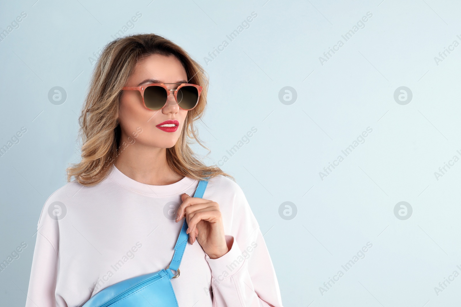 Photo of Young woman wearing stylish sunglasses on light grey background. Space for text