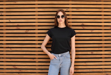 Young woman wearing black t-shirt against wooden wall on street. Urban style