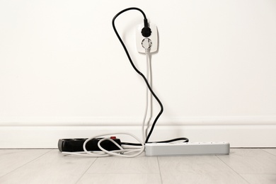 Photo of Extension cords with power plugs in socket indoors. Electrician's professional equipment