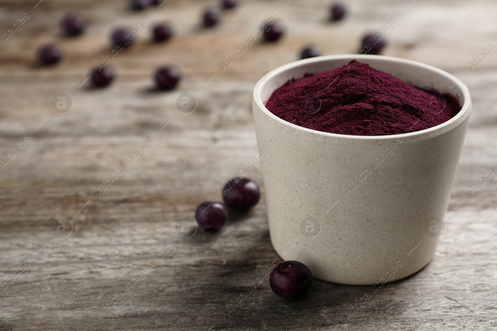 Photo of Bowl with acai powder on wooden table