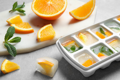 Photo of Ice cubes with orange and mint on light table, closeup