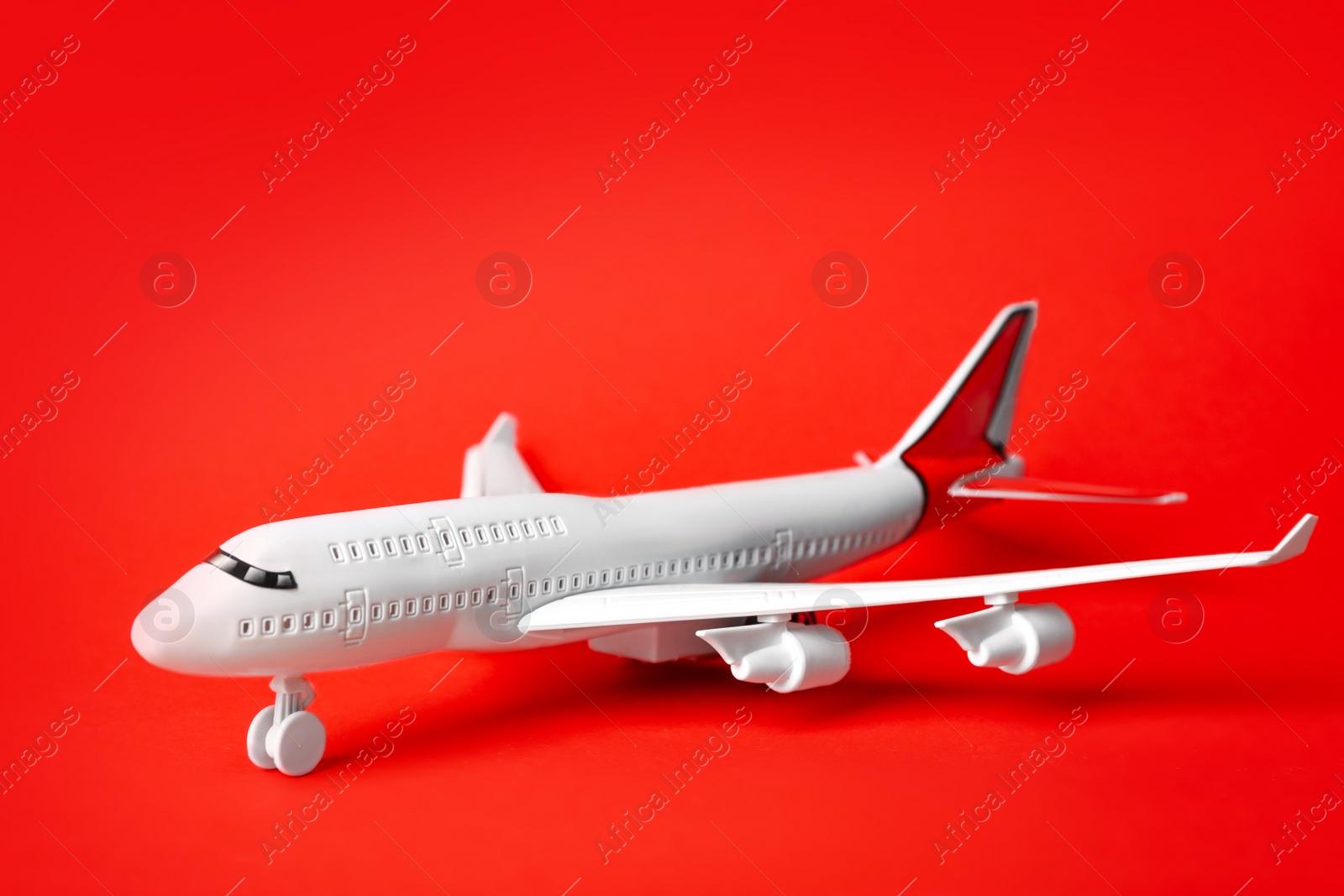 Photo of Toy plane on red background. Logistics and wholesale concept