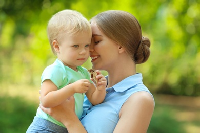 Young mother with her cute child in green park