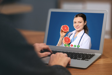 Woman using laptop for online consultation with nutritionist via video chat, closeup