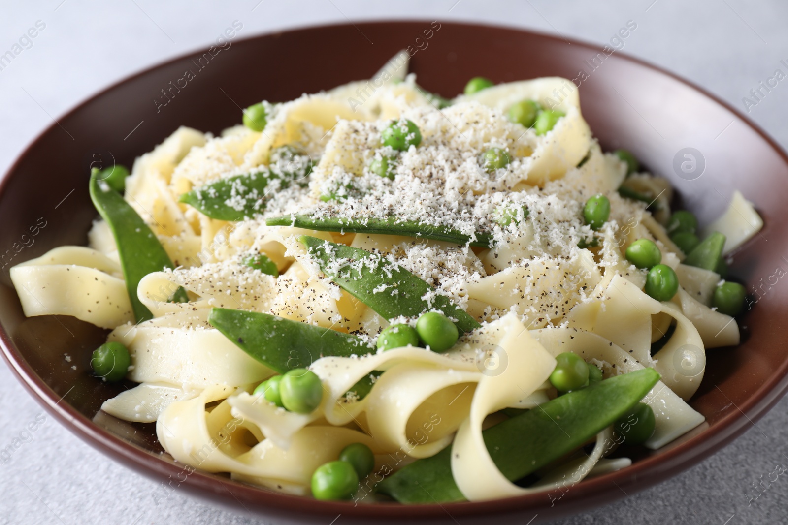 Photo of Delicious pasta with green peas and cheese on grey table, closeup