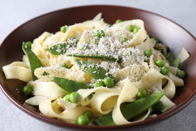 Delicious pasta with green peas and cheese on grey table, closeup