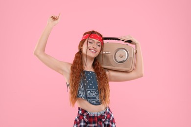 Photo of Stylish young hippie woman with retro radio receiver on pink background