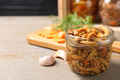 Photo of Delicious marinated mushrooms in glass jar on wooden table. Space for text