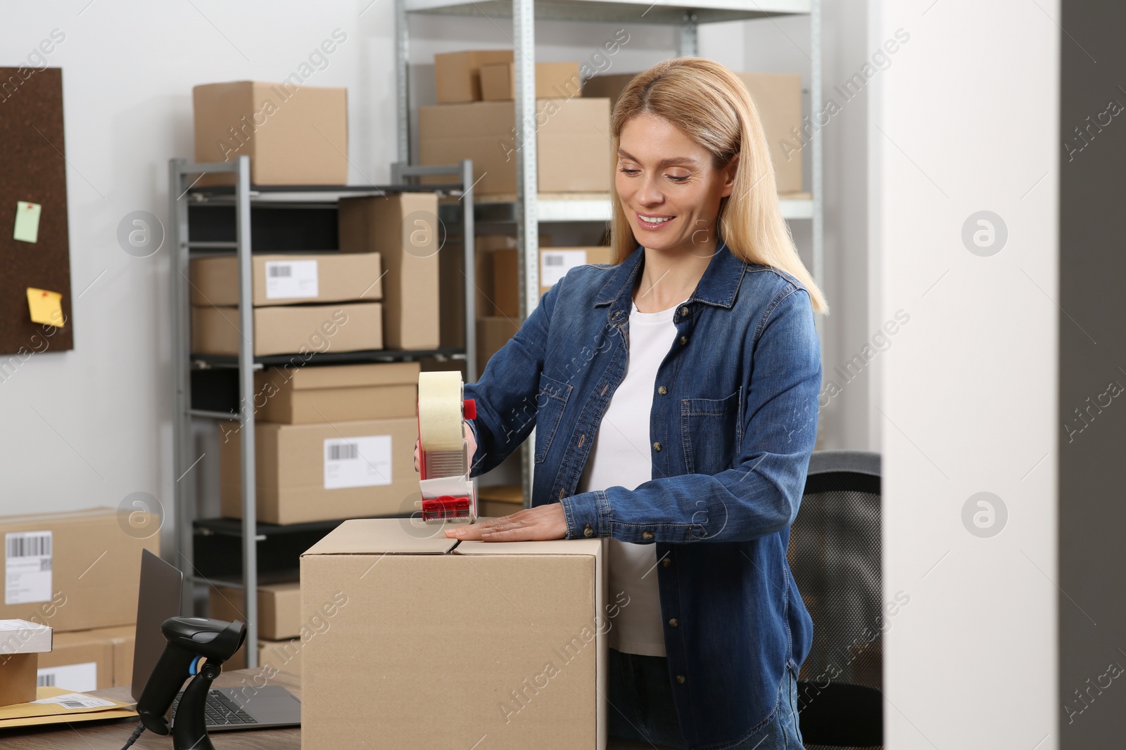 Photo of Seller taping parcel in office. Online store