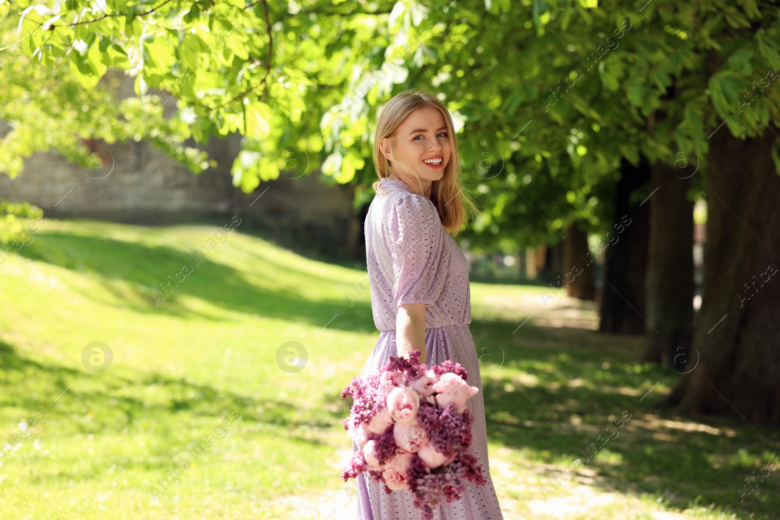 Photo of Beautiful woman with bouquet of spring flowers in park on sunny day