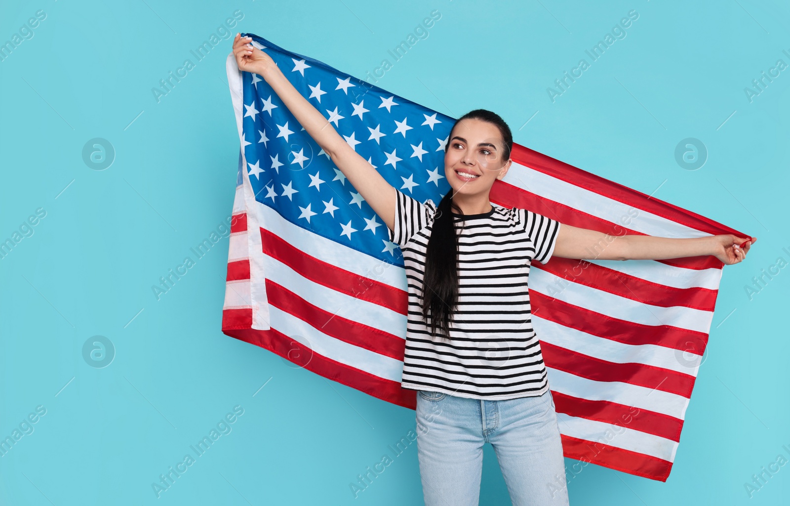 Photo of 4th of July - Independence Day of USA. Happy woman with American flag on light blue background, space for text