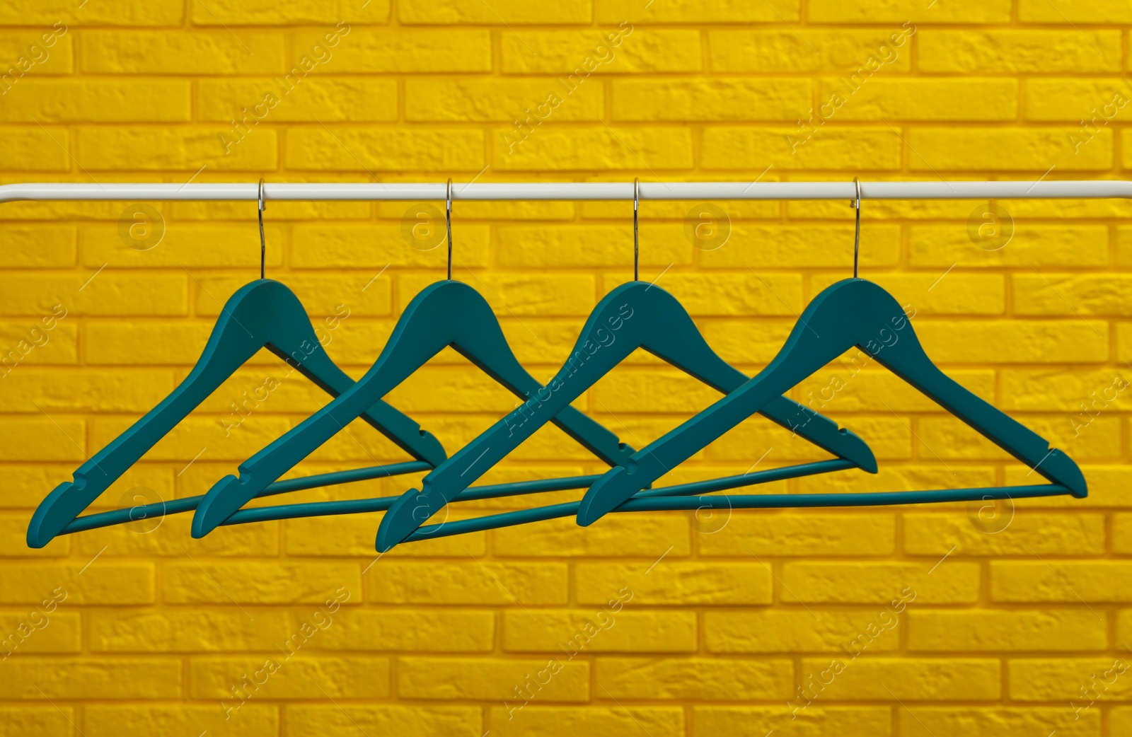 Photo of Wardrobe rack with many hangers near yellow brick wall