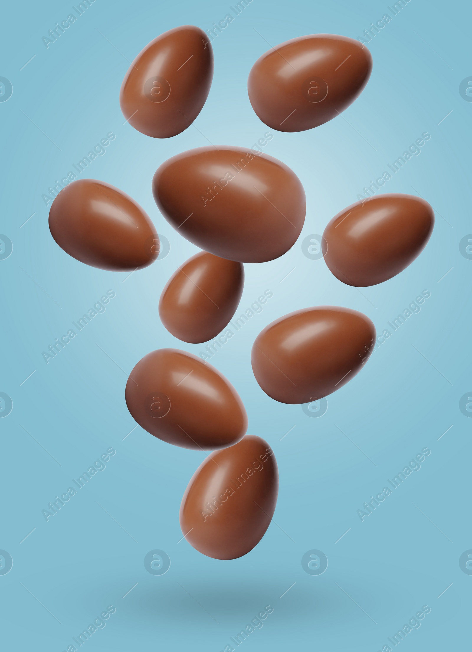 Image of Many chocolate eggs falling on light blue background