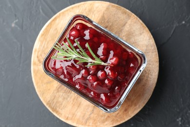 Fresh cranberry sauce and rosemary in glass bowl on gray textured table, top view