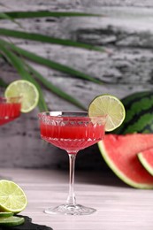 Photo of Cocktail glass of delicious fresh watermelon juice with lime on light wooden table