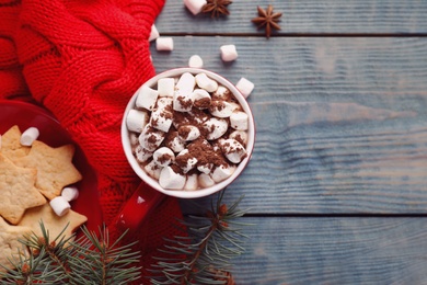 Flat lay composition of tasty cocoa with marshmallows on blue wooden table. Space for text