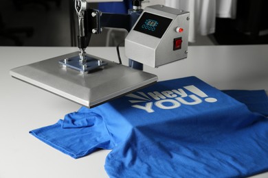 Printing logo. Heat press with blue t-shirt on white table