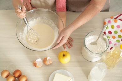 Little girl and her grandmother cooking at table with products, top view