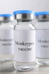 Monkeypox vaccine in glass vials on wooden table, closeup