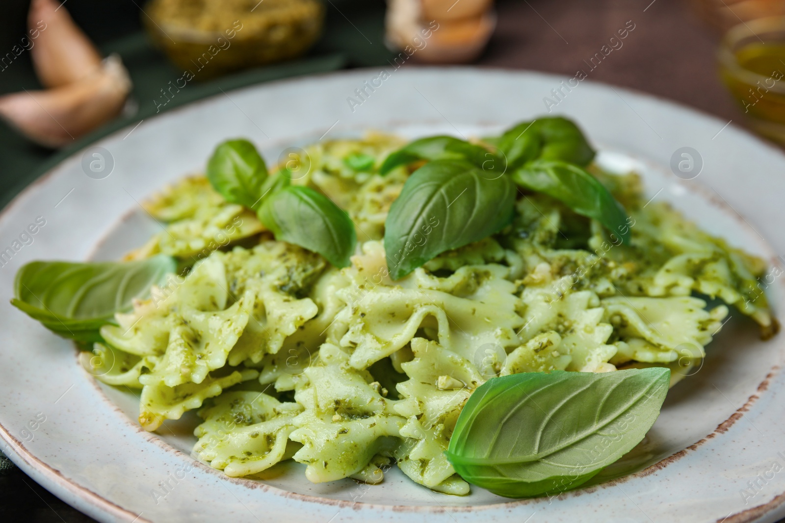 Photo of Delicious pasta with pesto sauce and basil on table, closeup