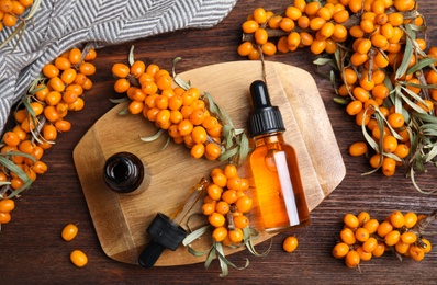 Flat lay composition with sea buckthorn oil on wooden table