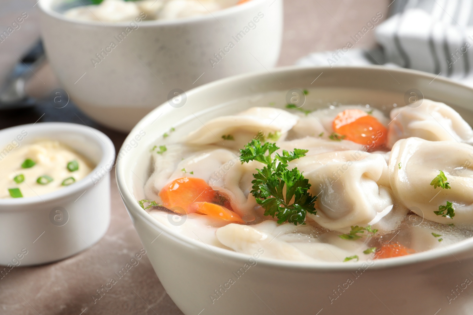 Photo of Bowl of tasty dumplings in broth on table, closeup. Space for text