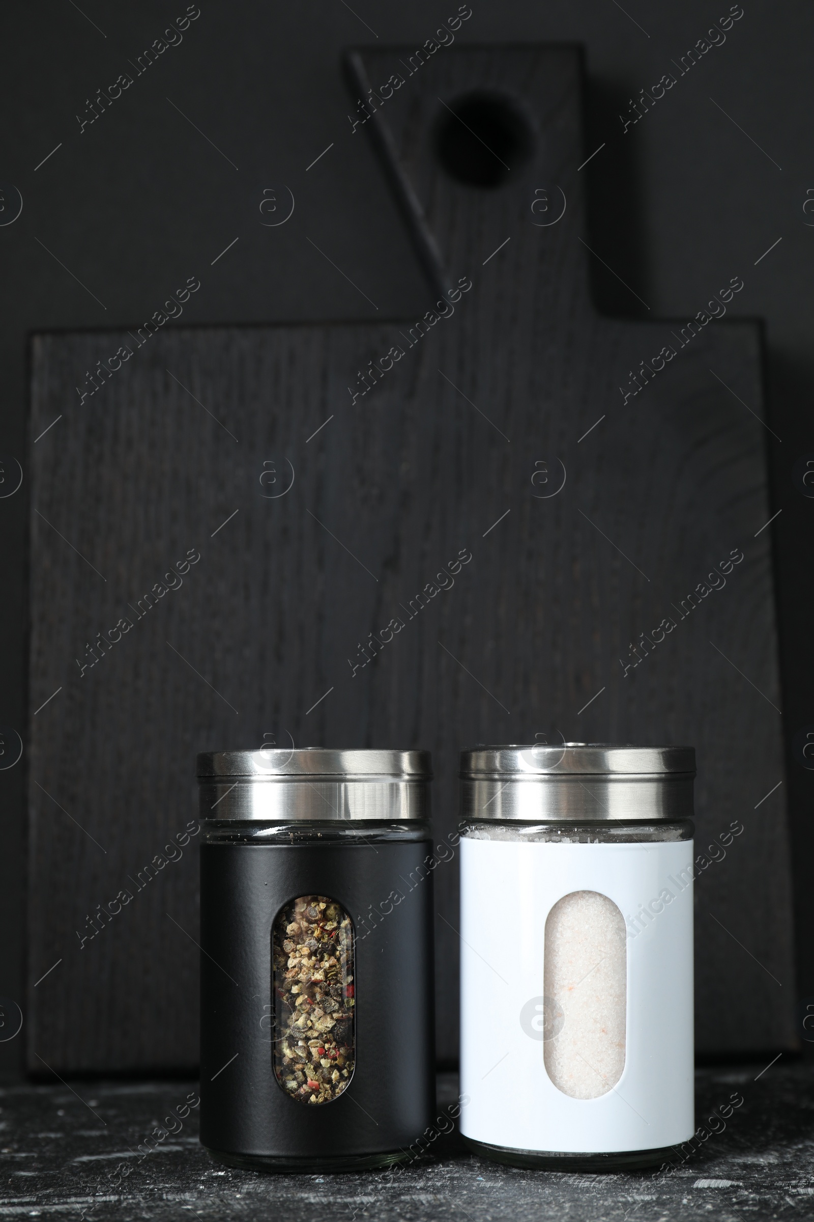 Photo of Salt and pepper shakers on dark table