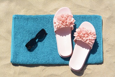 Towel, flip flops and sunglasses on sand, top view. Beach accessories