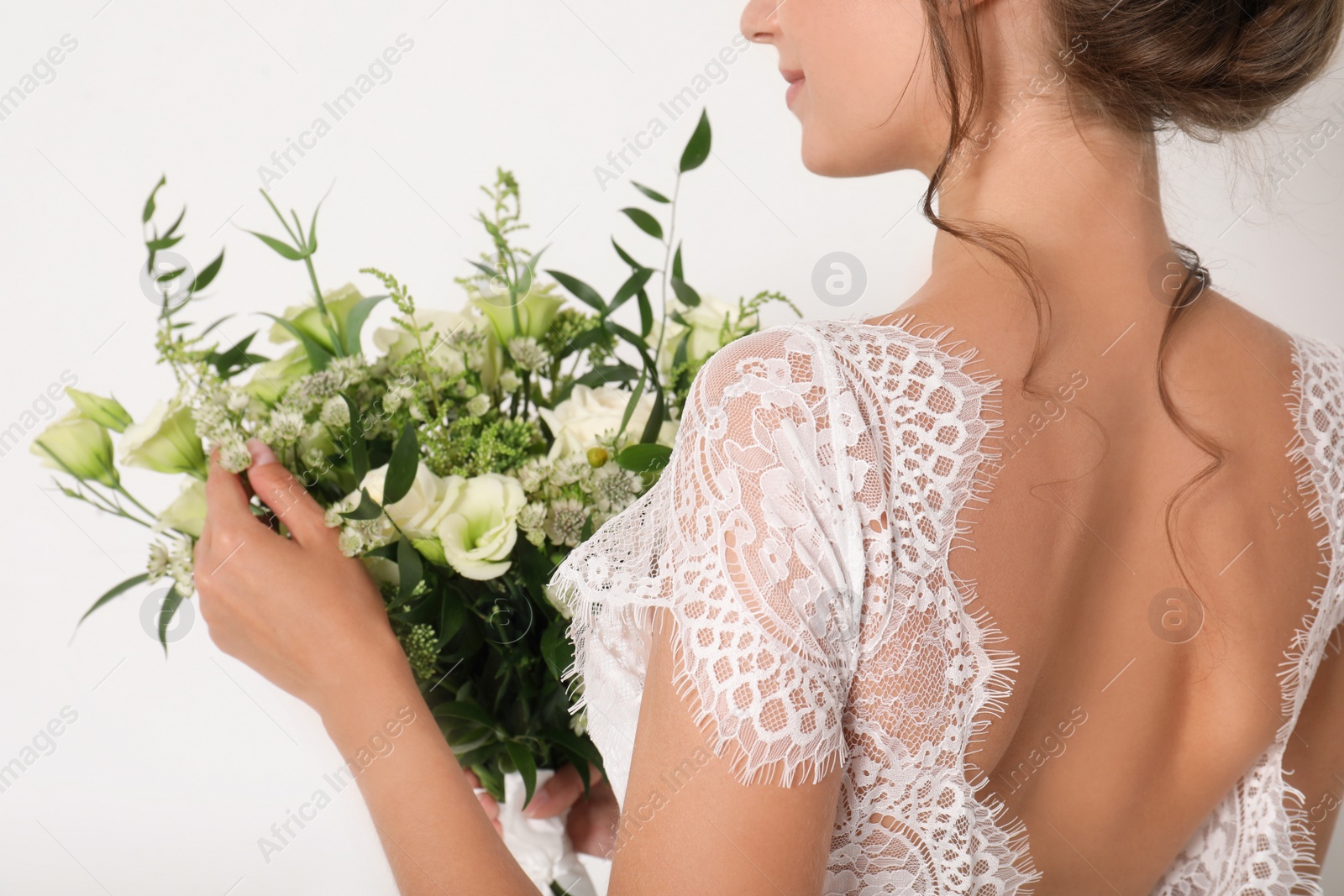 Photo of Young bride wearing wedding dress with beautiful bouquet on light background, closeup