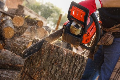Man sawing wooden log outdoors, closeup view