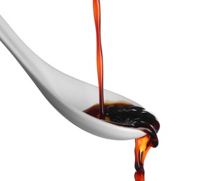 Pouring soy sauce into spoon against white background