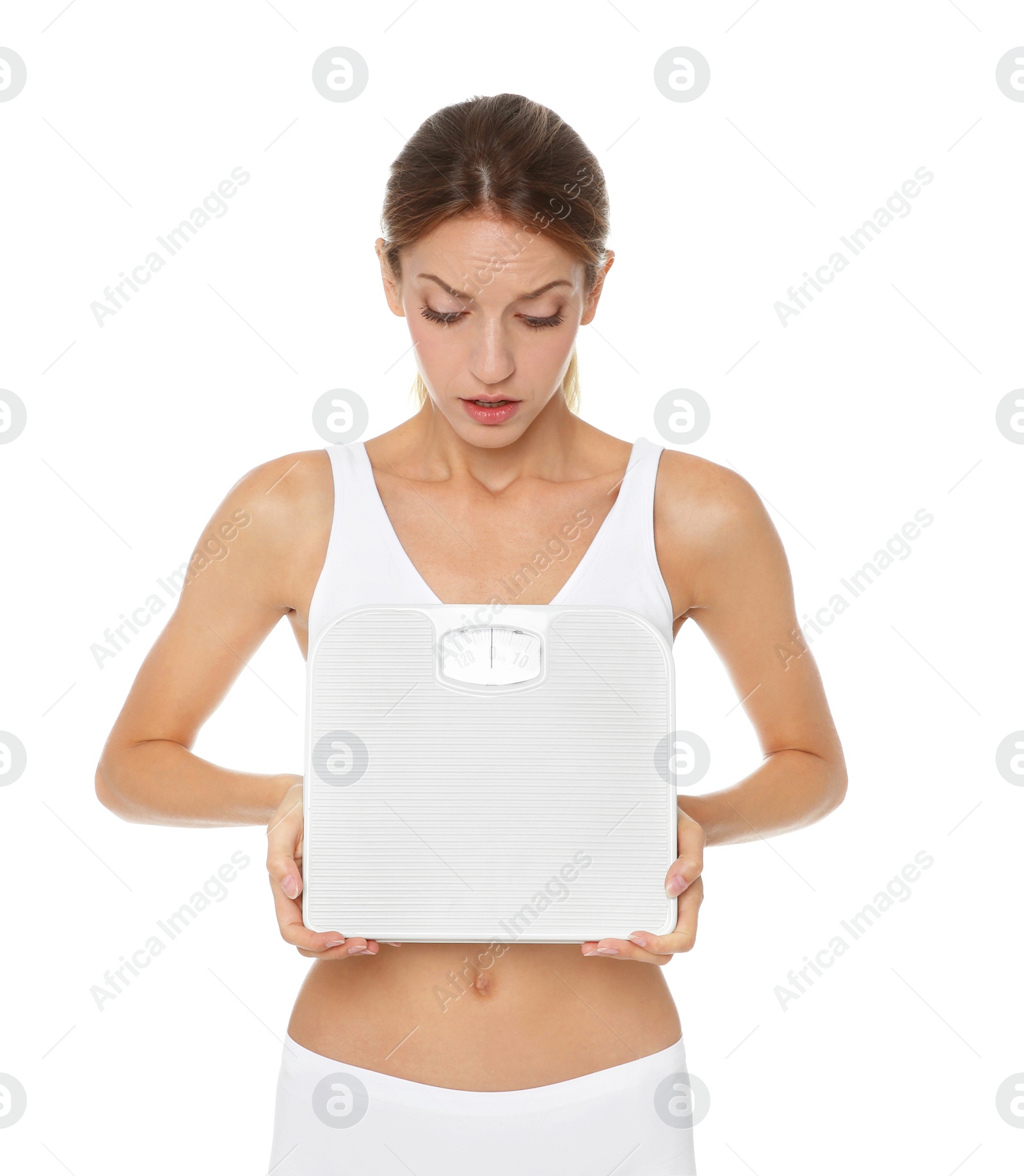 Photo of Worried young woman holding bathroom scales on white background. Weight loss diet