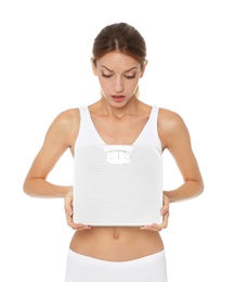 Photo of Worried young woman holding bathroom scales on white background. Weight loss diet