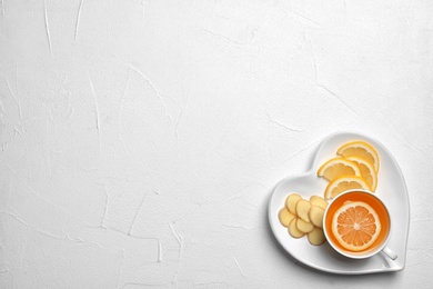 Plate with cup of tea, lemon and ginger on white background, top view. Space for text